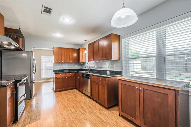 a large kitchen with stainless steel appliances granite countertop a sink dishwasher a stove and a refrigerator