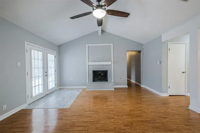 a view of an empty room with window and kitchen view