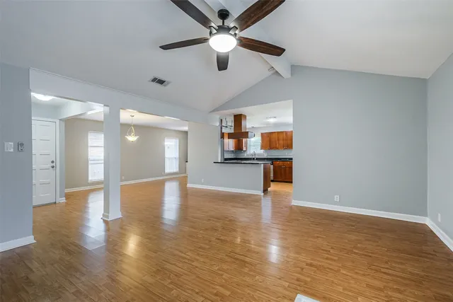 a view of an empty room with window and wooden floor