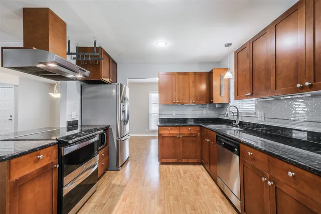 a kitchen with stainless steel appliances granite countertop a stove top oven a sink and dishwasher a oven with wooden floors