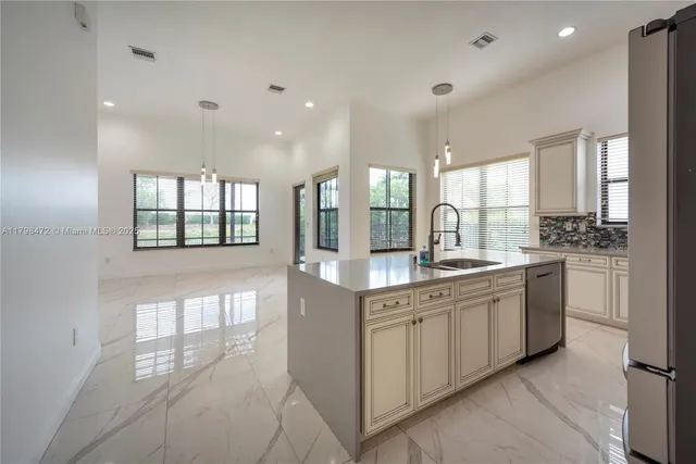 a kitchen with granite countertop a sink stainless steel appliances and white cabinets