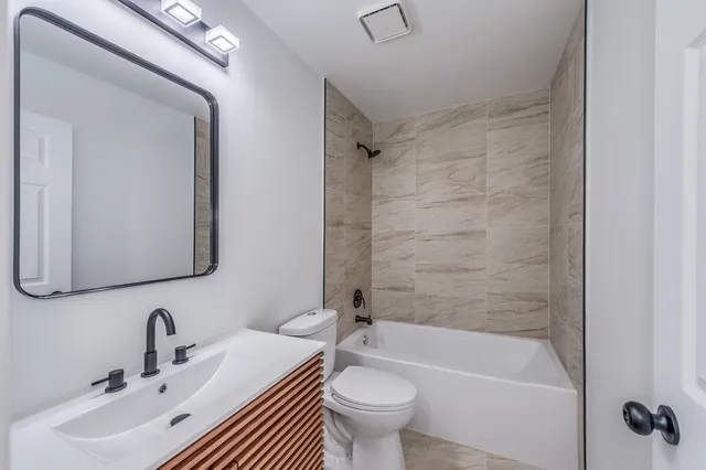 a bathroom with a bathtub shower sink mirror vanity and toilet