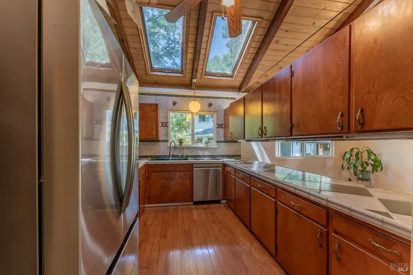 a kitchen with stainless steel appliances granite countertop a refrigerator a sink and wooden cabinets