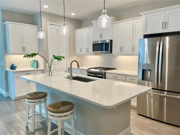 a kitchen with kitchen island a sink a stove and chairs
