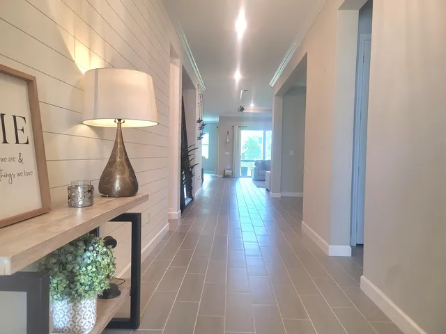 a hallway with wooden floor windows and a table