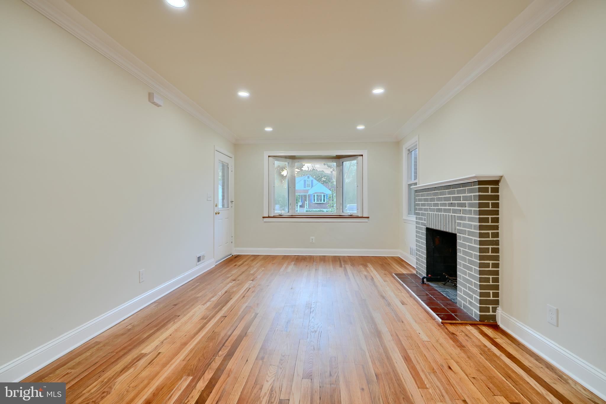 6409 Eastern Parkway Baltimore, MD 21214 - Photo 8 of 56 an empty room with wooden floor fireplace and windows