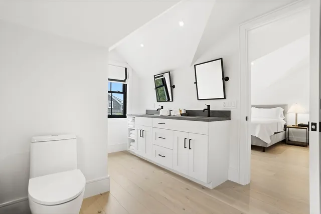 a bathroom with a granite countertop sink mirror vanity and toilet
