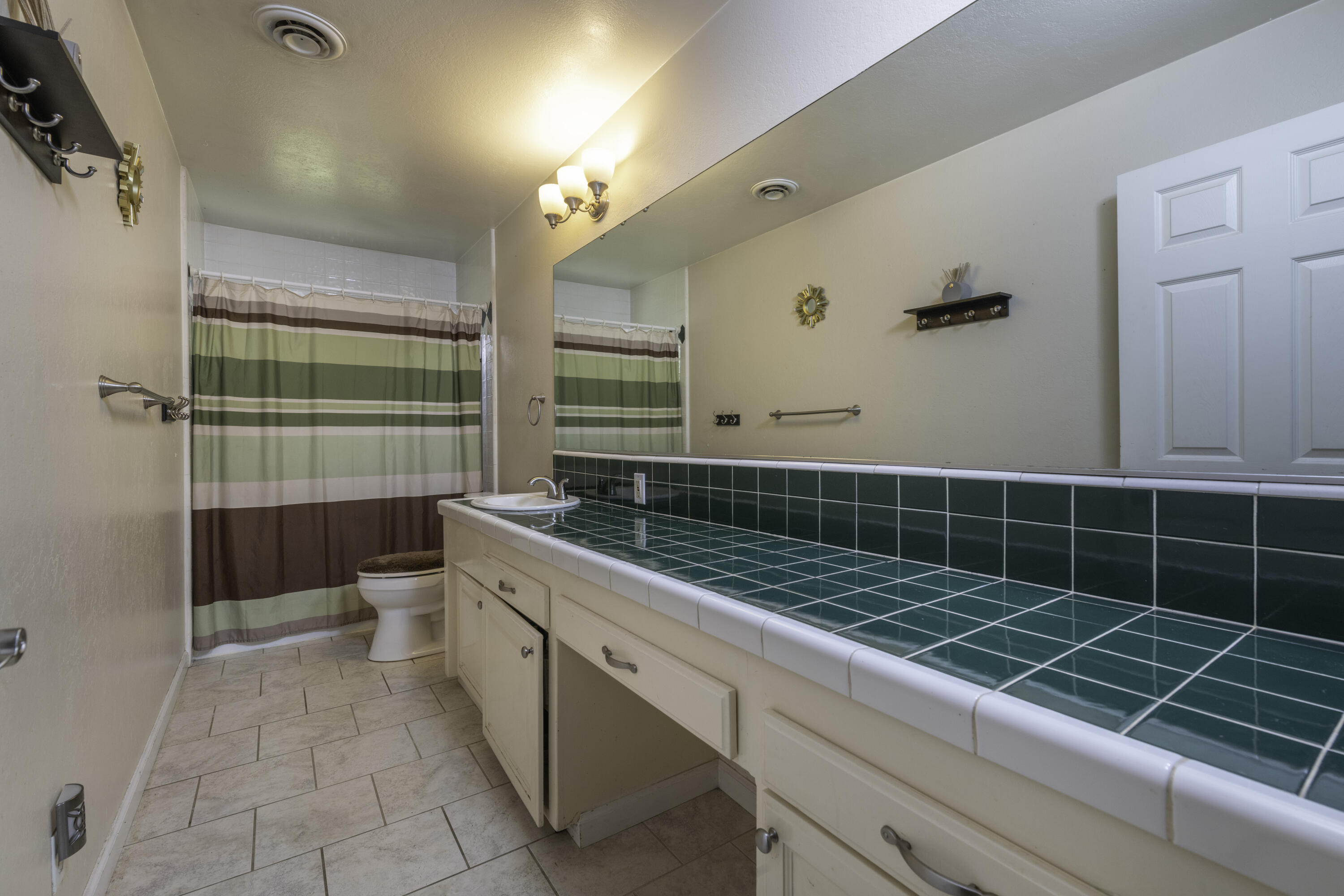 2816 Squire Avenue Redding, CA 96002 - Photo 6 of 13 a bathroom with a bathtub a mirror a vanity and a shower