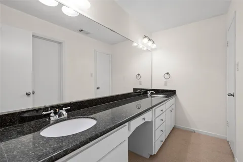 a bathroom with a granite countertop double vanity sink and a mirror