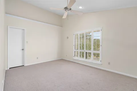 an empty room with a window and a ceiling fan
