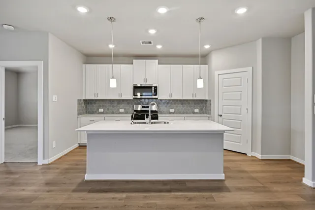 a view of kitchen with stainless steel appliances granite countertop cabinets and wooden floor