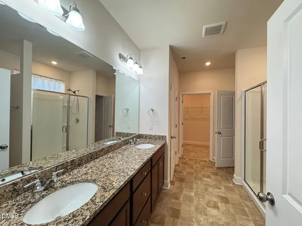 a bathroom with a granite countertop double vanity sink and mirror