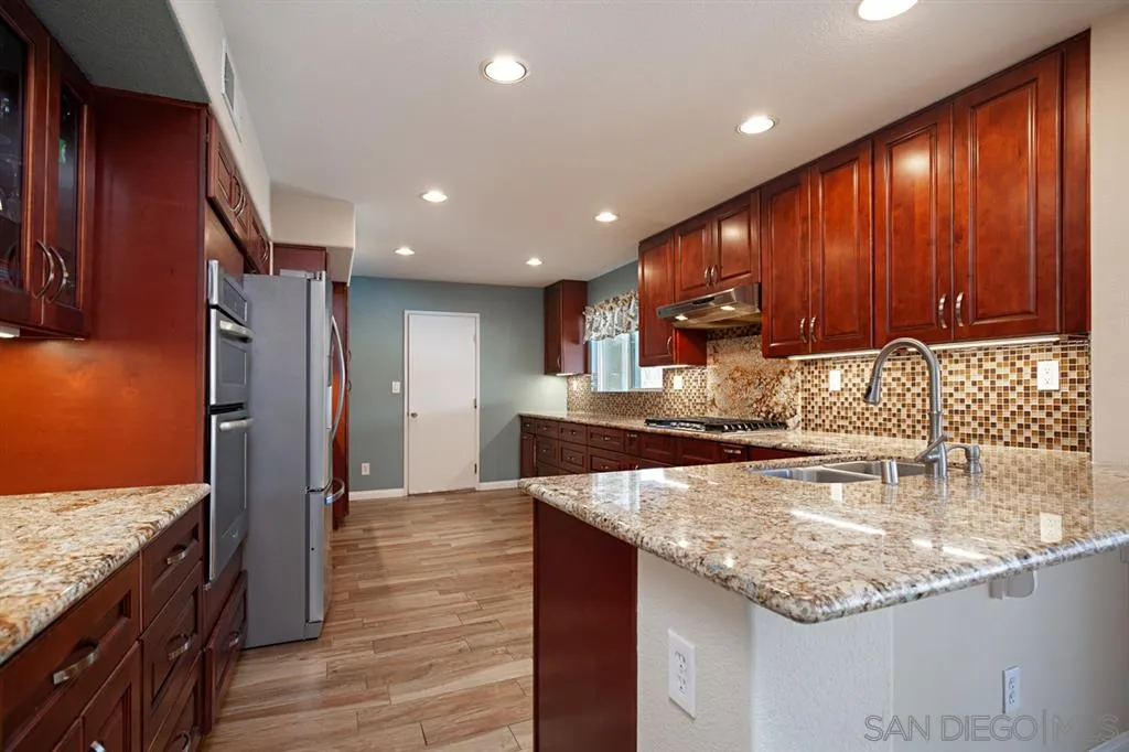 2170 Boulders Road Alpine, CA 91901 - Photo 4 of 24 a kitchen with stainless steel appliances granite countertop wooden cabinets a refrigerator and a sink