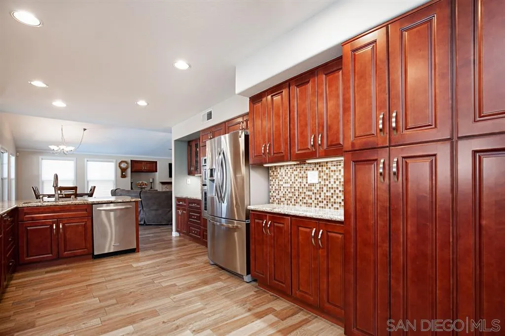2170 Boulders Road Alpine, CA 91901 - Photo 6 of 24 a kitchen with stainless steel appliances granite countertop wooden floors and wooden cabinets