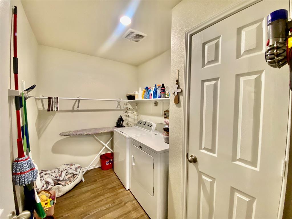 110 West Point Way Elgin, TX 78621 - Photo 15 of 19 A dedicated laundry space displays wood style flooring and functional built-in shelving.