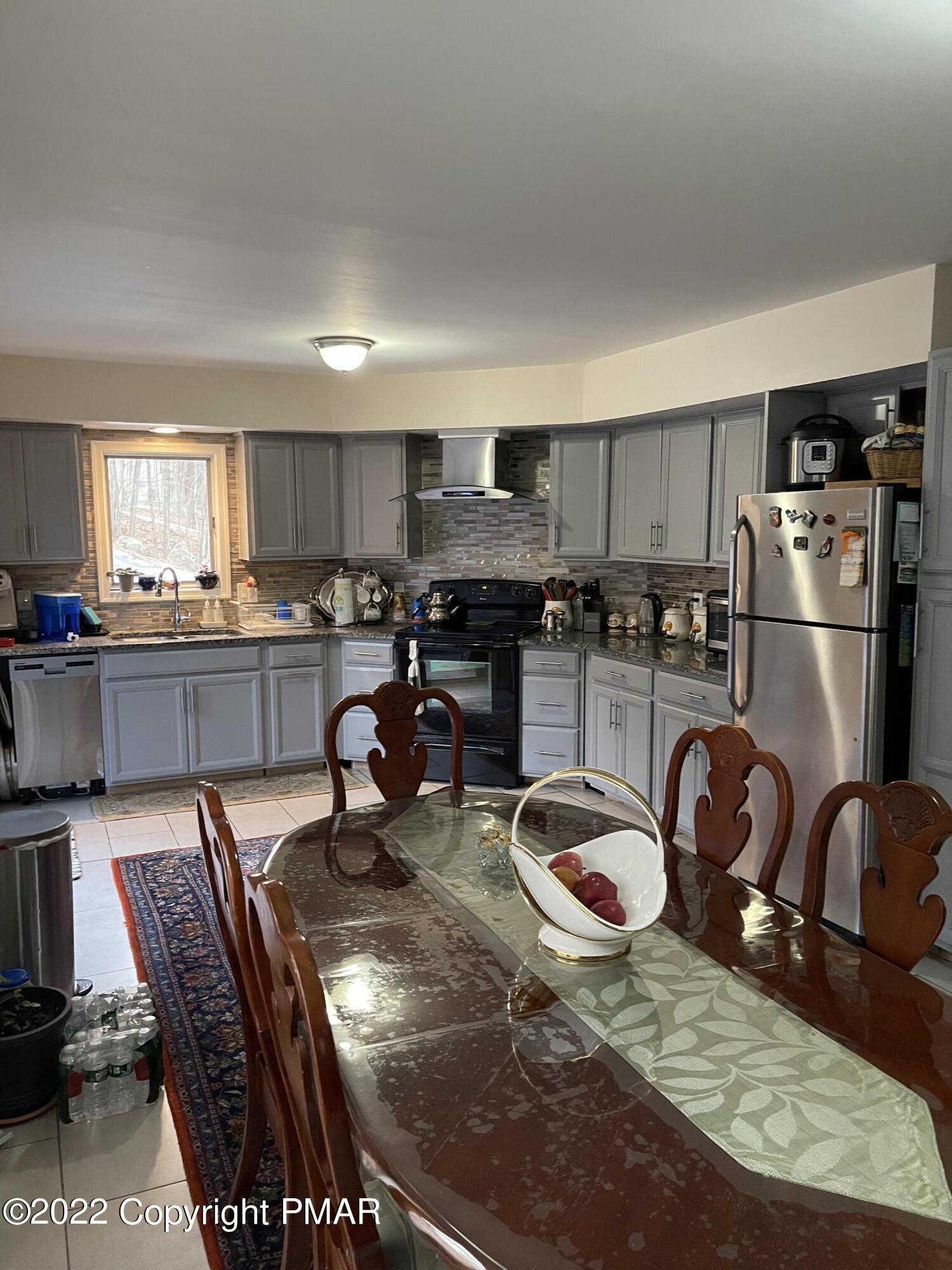 5665 Decker Road Bushkill, PA 18324 - Photo 6 of 32 a kitchen with stainless steel appliances granite countertop a sink a stove a refrigerator cabinets a dining table and chairs