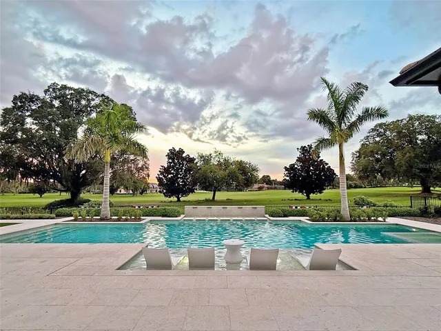 a living room with couches floor to ceiling window and a flat screen tv