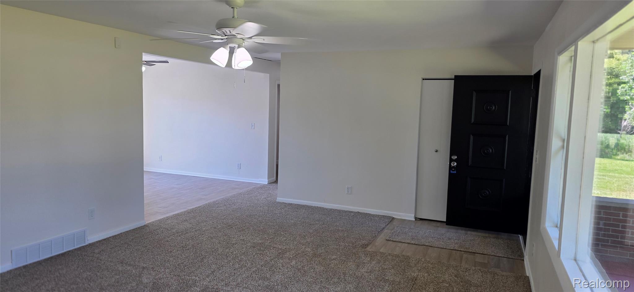 4363 West Dodge Road Clio, MI 48420 - Photo 7 of 52 Spacious room featuring neutral carpeting, a ceiling fan, and a dark paneled entry door