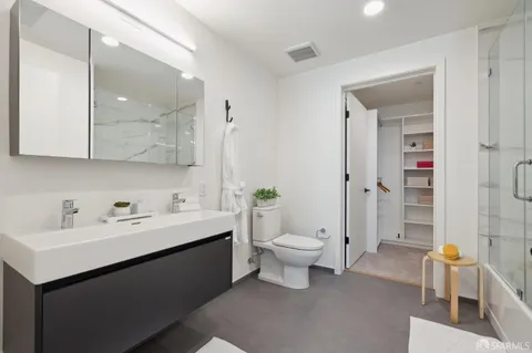 a bathroom with a toilet sink double vanity and mirror
