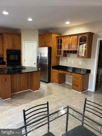 a kitchen with stainless steel appliances granite countertop a refrigerator a stove a sink a counter space and cabinets