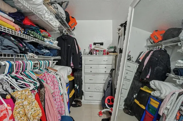 a view of walk in closet with clothes and shoes