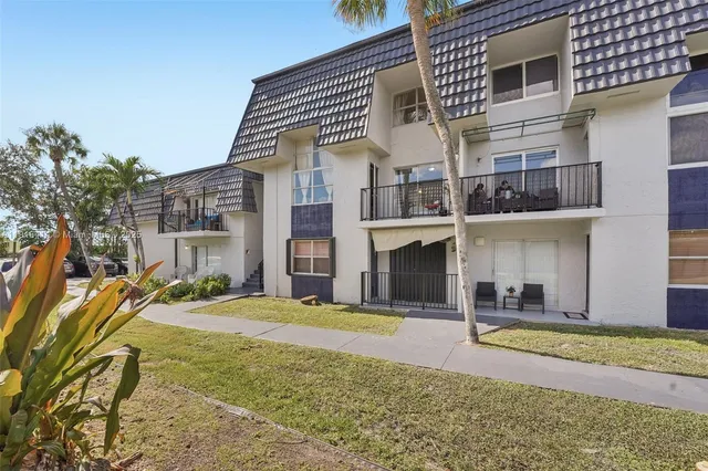a view of a pathway with flower garden in front of house