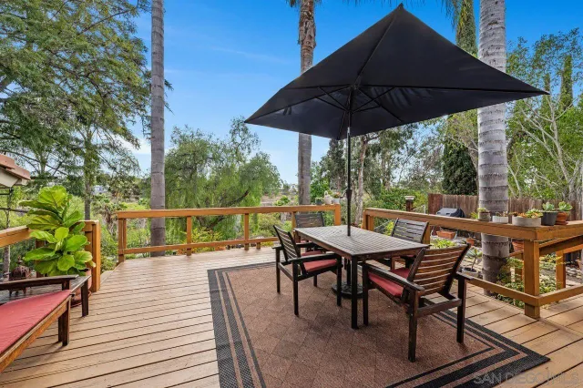 a view of deck with dinning table and chairs under an umbrella
