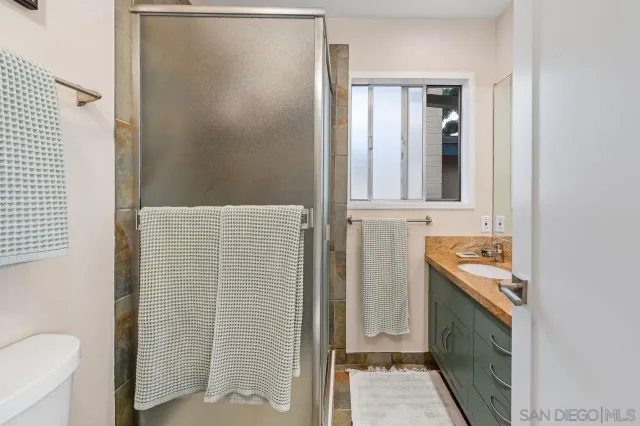 a bathroom with a granite countertop sink a toilet and shower