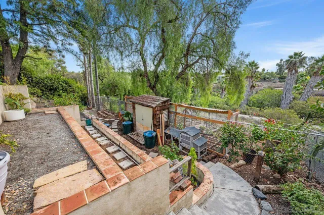 a view of a patio with table and chairs plants and large trees