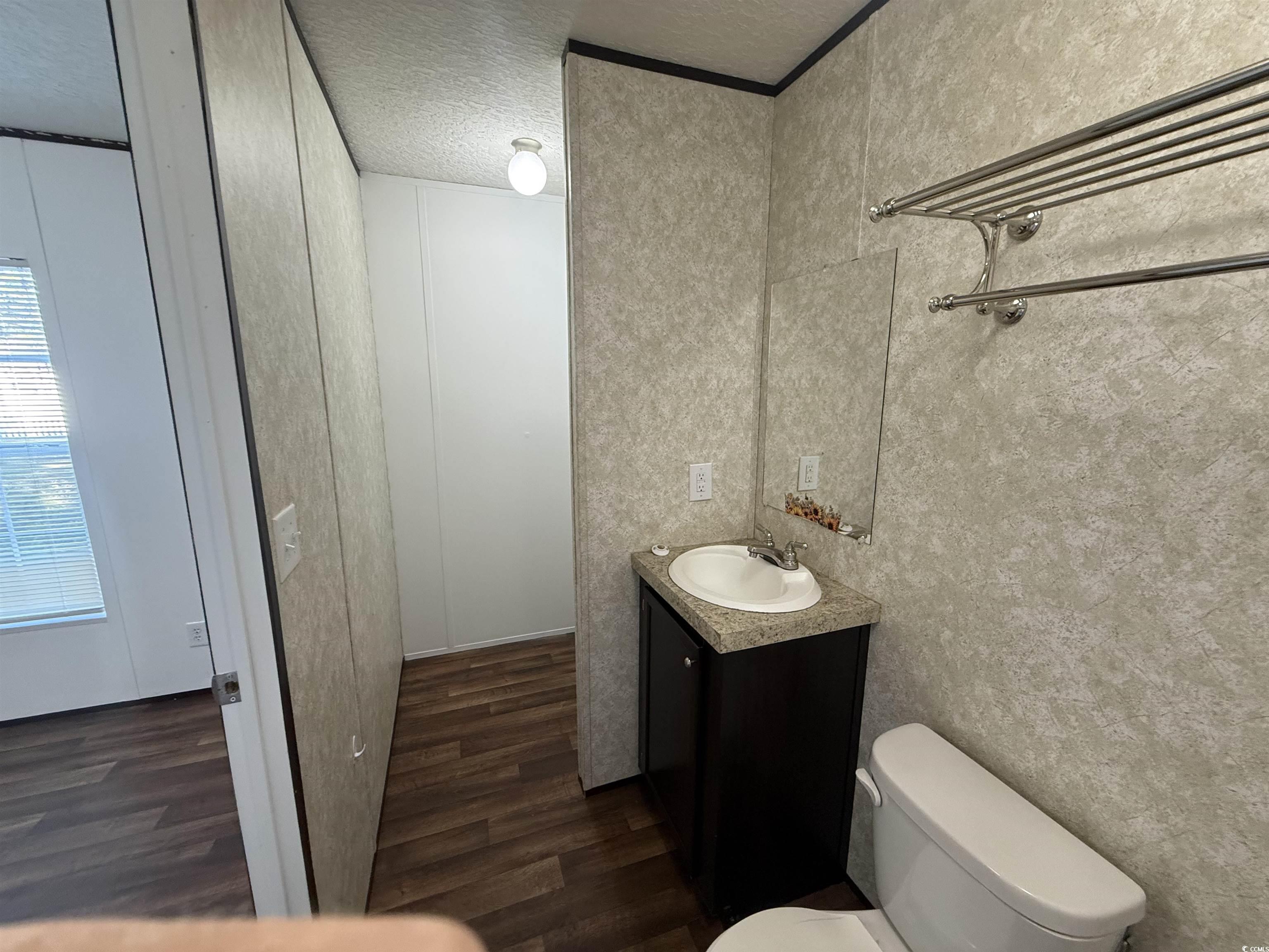 380 Hangar Court Myrtle Beach, SC 29577 - Photo 11 of 16 Half bath featuring vanity, dark wood-style floors, and a textured ceiling