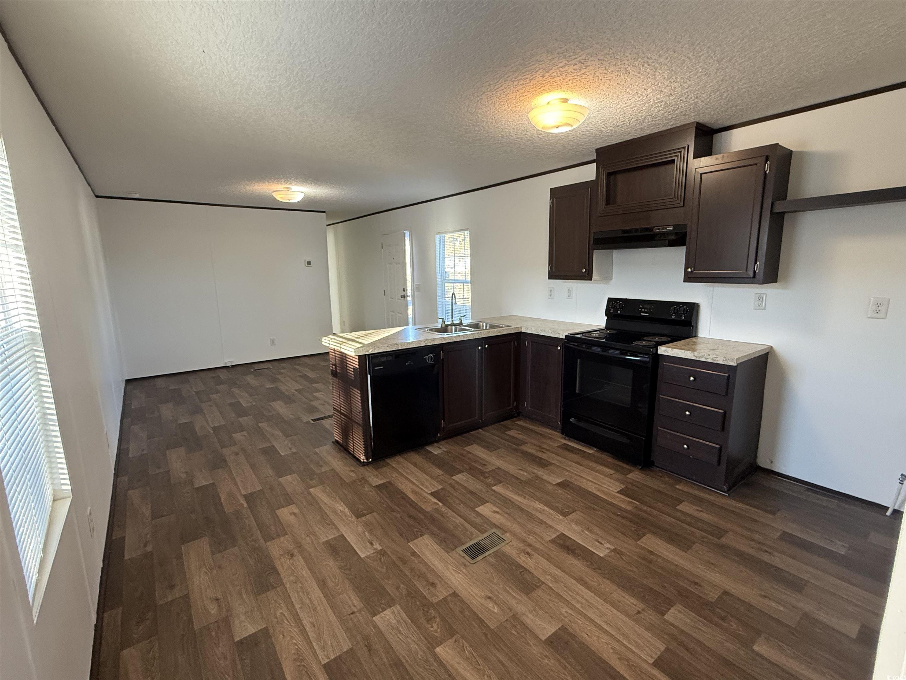 380 Hangar Court Myrtle Beach, SC 29577 - Photo 5 of 16 Kitchen featuring light countertops, dark brown cabinets, a peninsula, black appliances, and a textured ceiling