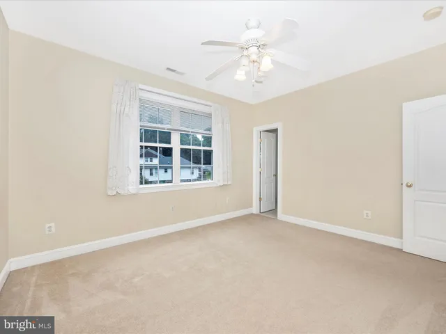 an empty room with windows and chandelier fan