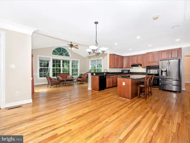 a open kitchen view with stainless steel appliances granite countertop a stove and a wooden floors