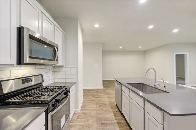 a kitchen with stainless steel appliances granite countertop a sink stove and microwave