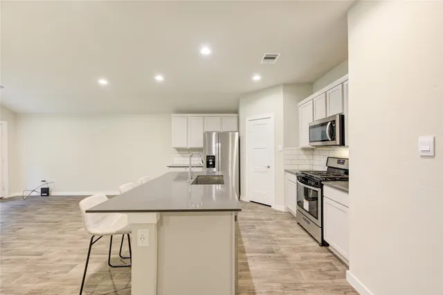 a kitchen with stainless steel appliances granite countertop a stove a refrigerator a sink a oven with a dining table and chairs