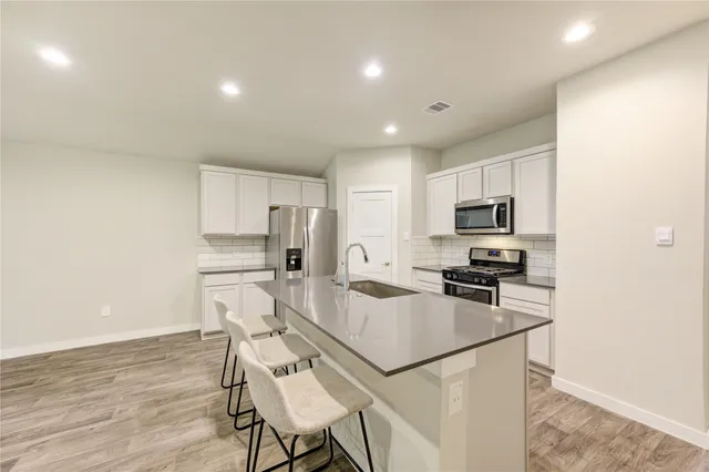 a kitchen with stainless steel appliances a refrigerator stove microwave and white cabinets