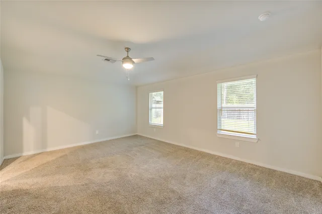 an empty room with a window and a ceiling fan