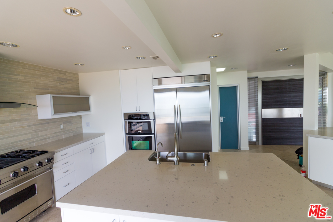 20534 Roca Chica Drive Malibu, CA 90265 - Photo 22 of 38 a kitchen with stainless steel appliances kitchen island granite countertop a refrigerator and a stove top oven