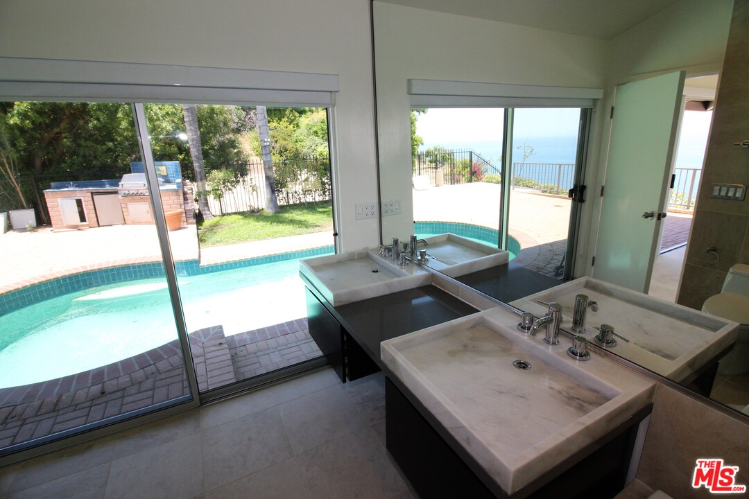 20534 Roca Chica Drive Malibu, CA 90265 - Photo 9 of 38 a bathroom with a sink and a large mirror next to a yard
