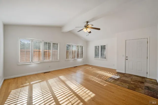 a view of an empty room with a window and wooden floor
