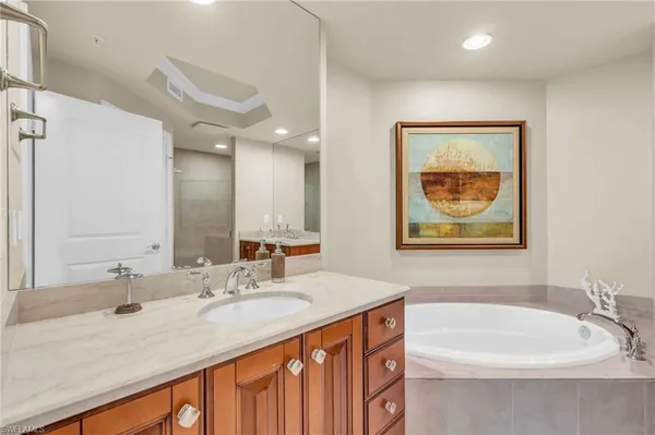 a bathroom with a double vanity sink mirror and bathtub