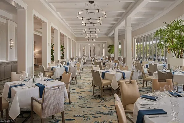 a view of a dining room with furniture a chandelier and large windows