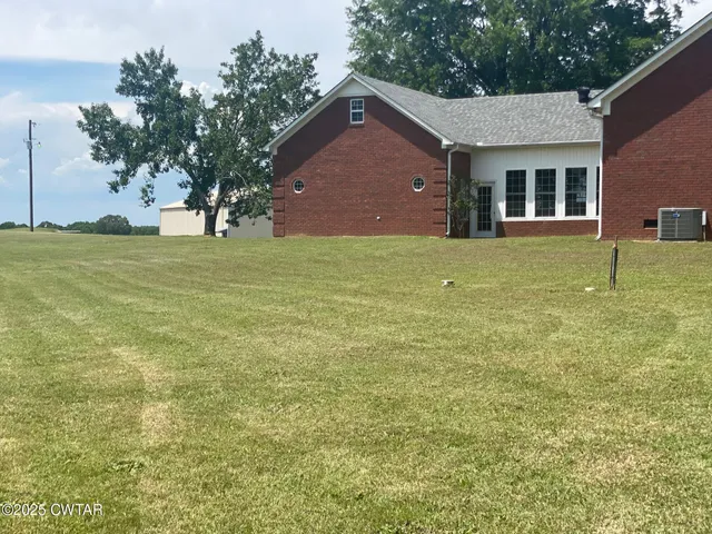 a front view of house with yard and trees in the background
