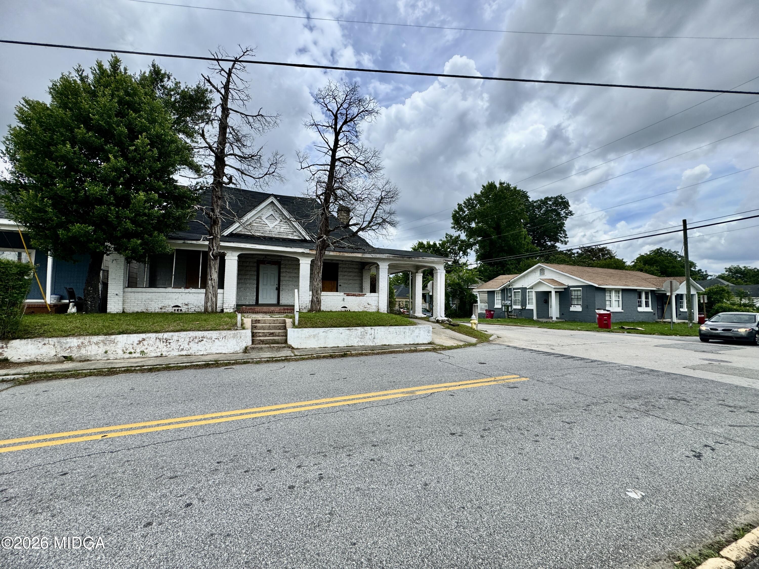 a front view of a house with a garden and a tree