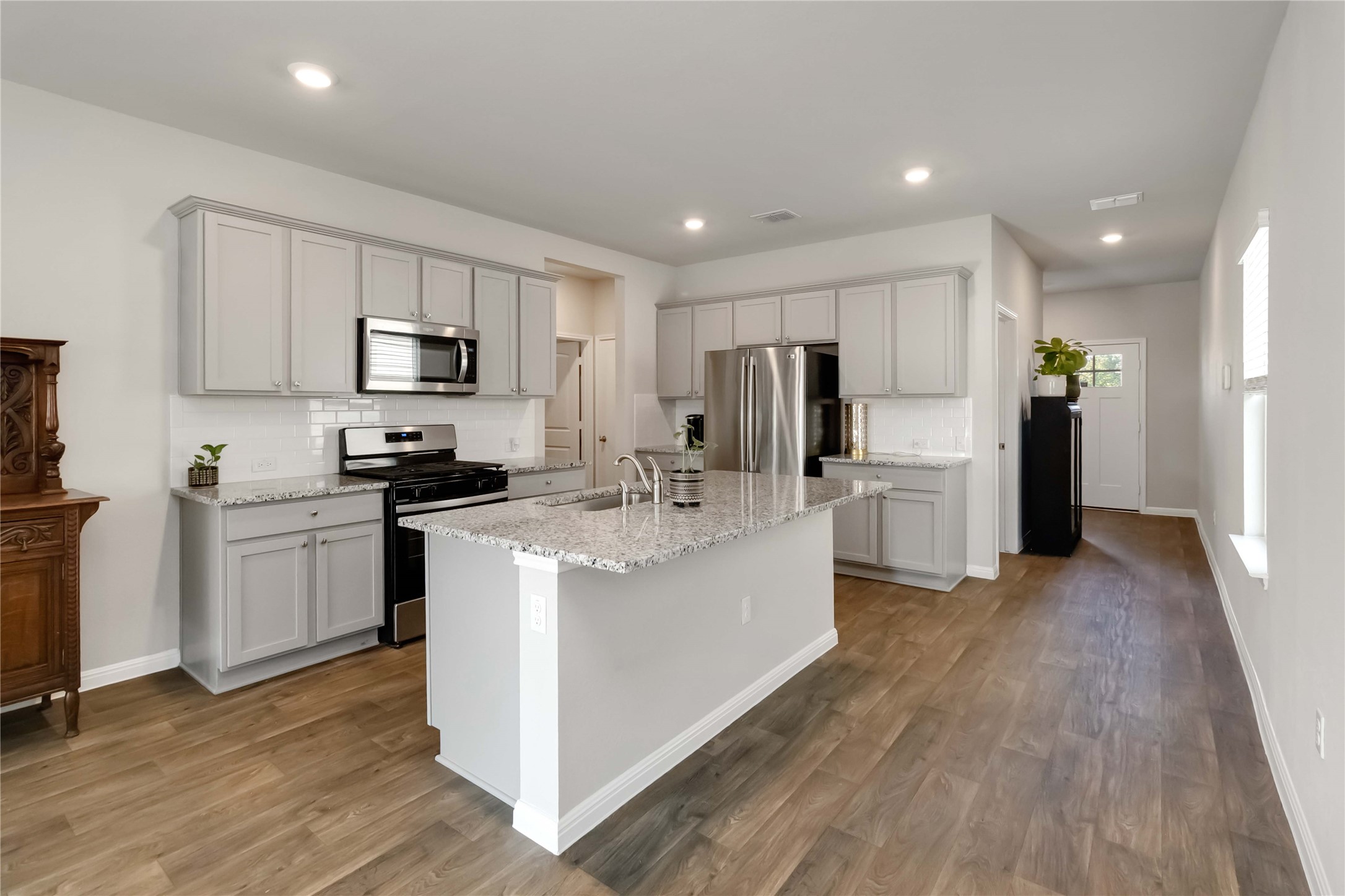103 Mariners Landing Bastrop, TX 78602 - Photo 5 of 25 a kitchen with kitchen island white cabinets stainless steel appliances and wooden floor
