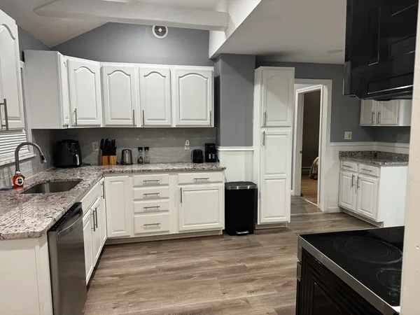 a kitchen with stainless steel appliances granite countertop a stove a sink dishwasher and a refrigerator with wooden cabinets