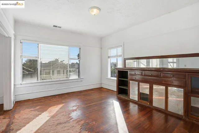 an empty room with wooden floor and windows