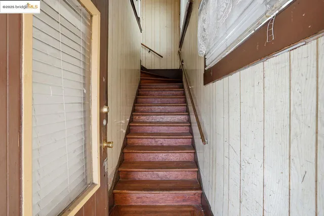 a view of staircase with wooden floor and white walls