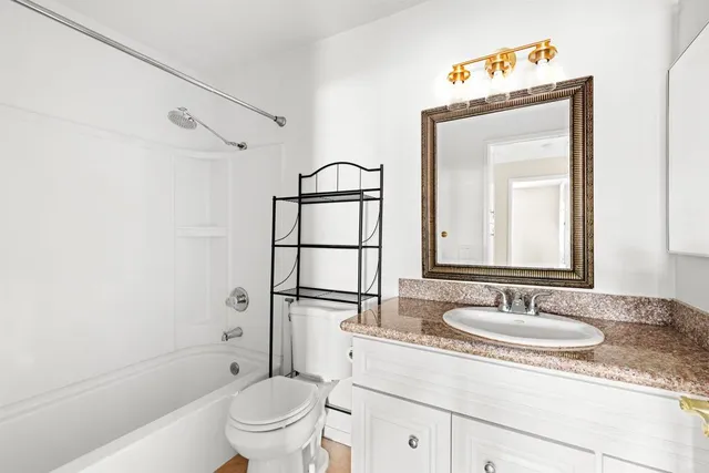 a bathroom with a granite countertop sink toilet mirror and shower
