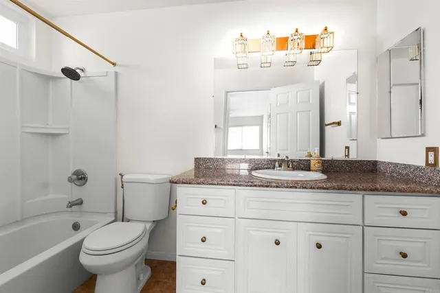 a bathroom with a granite countertop toilet a sink and a bathtub